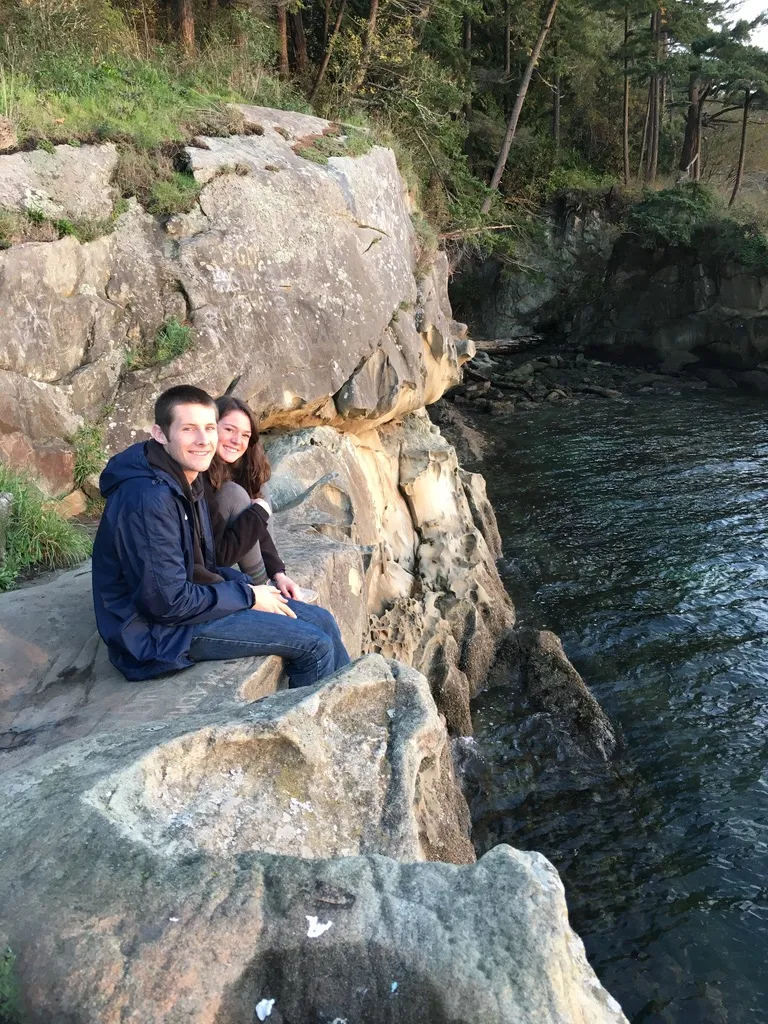 Haley and Stephen sitting together on a rocky shoreline